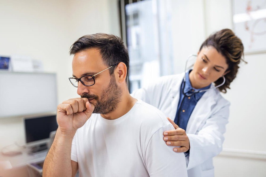 Man Coughing Whilst Being Checked By Doctor